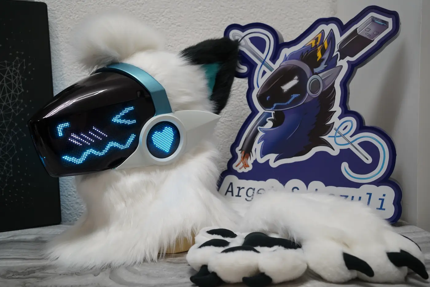 White Protogen head with black ears, a cyan LED face and a heart on the ear light, next to its white hand paws with black claws
