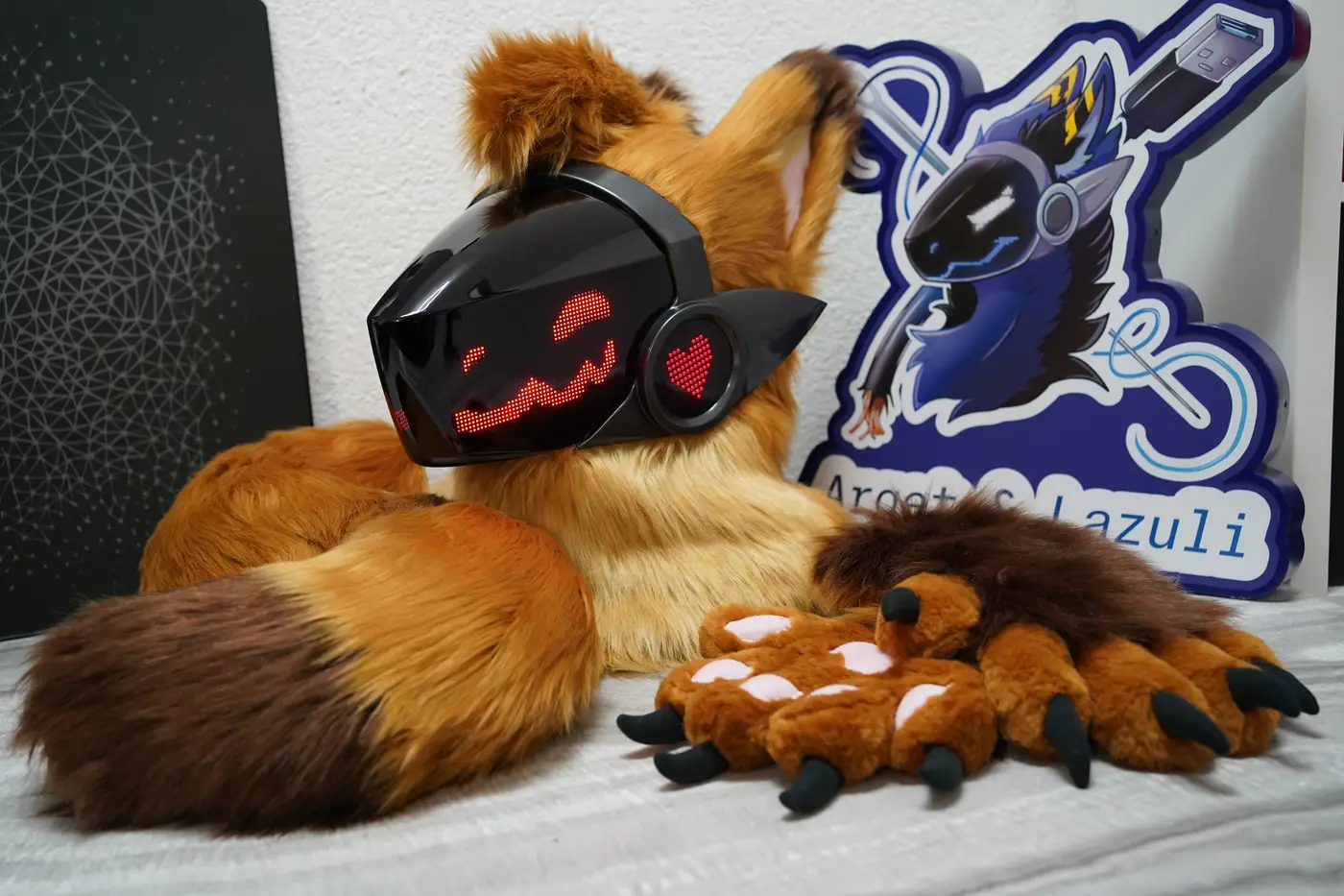 Tan Protogen mini partial with the head, brown tipped tail and clawed hand paws by the Arget and Lazuli logo