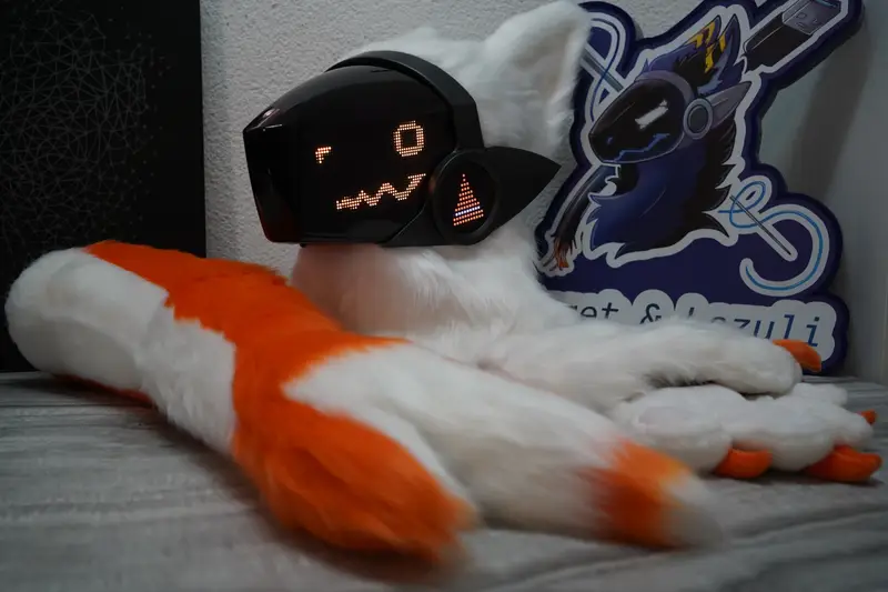 White Protogen head, hand paws and orange tail with the Arget and Lazuli logo