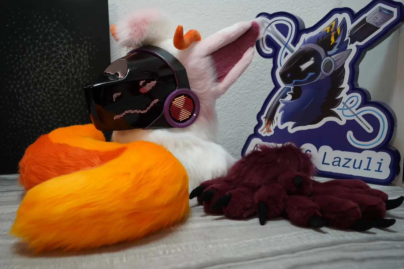 White and pink Protogen head, burgundy hand paws and orange tail with the Arget and Lazuli logo