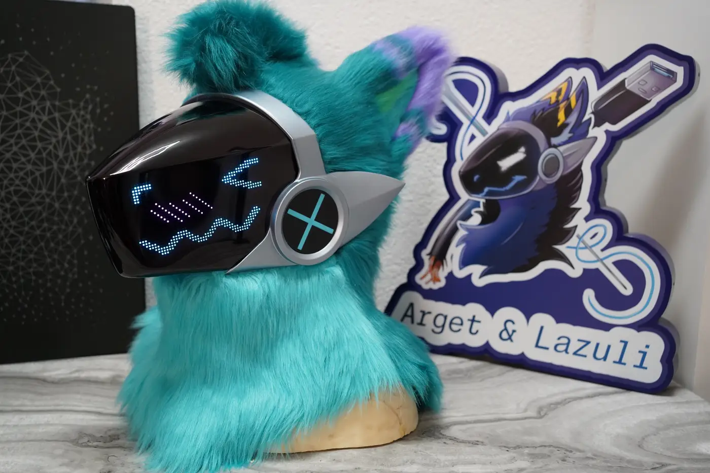 Turquoise Protogen head with purple ear tufts and a blue face on the silver framed LED visor