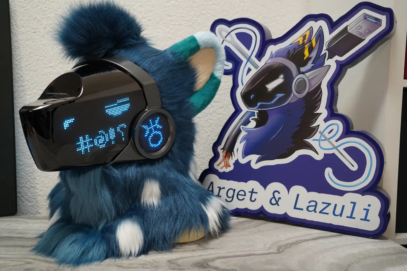 Dark teal Protogen head with blue pixel eyes and a row of pixel symbols for a mouth on the black LED visor