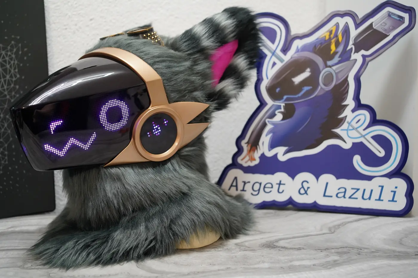 Grey Protogen head with a purple w shaped mouth and a round eye on the LED visor