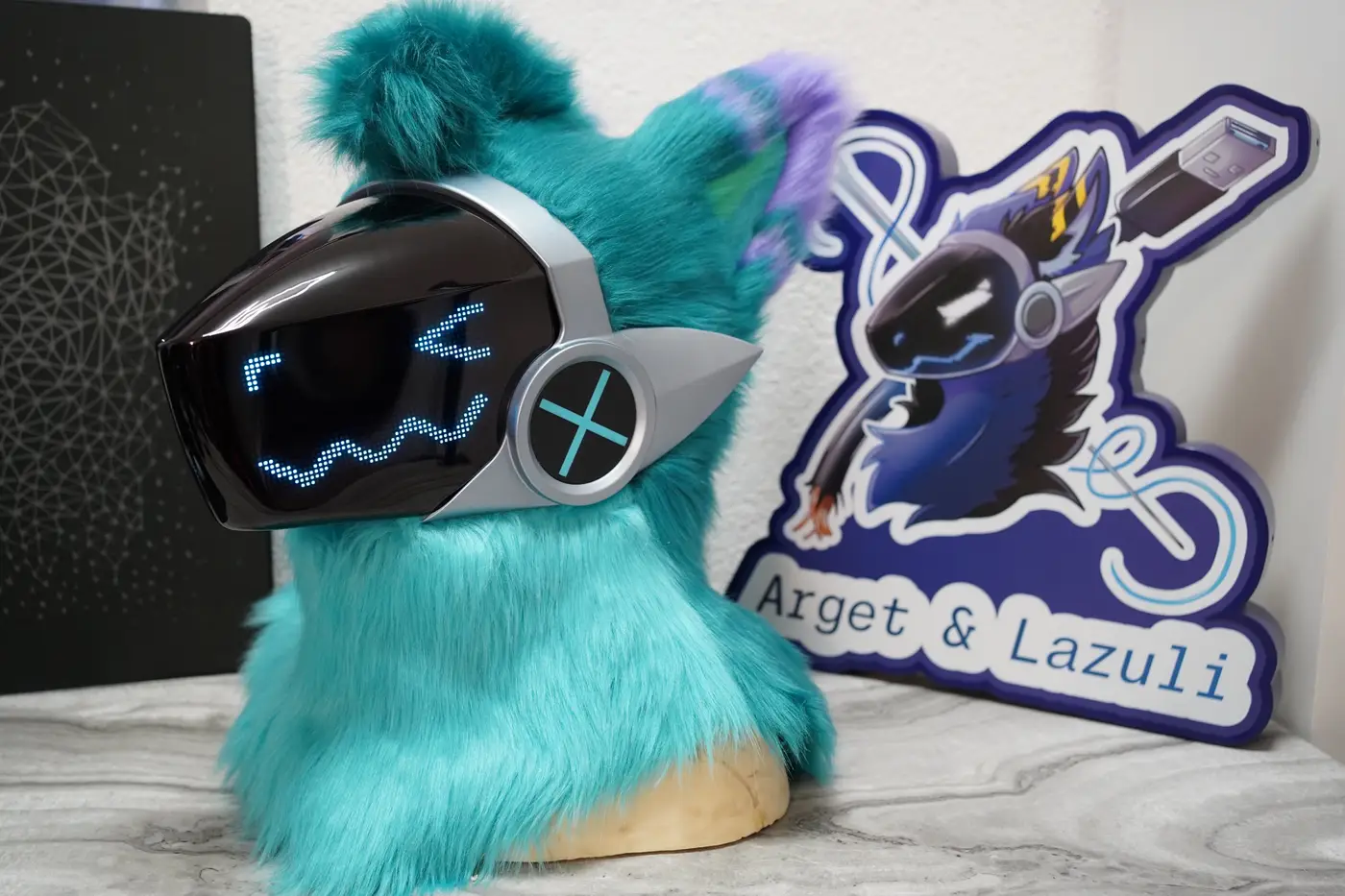 Turquoise Protogen head with small blue eyes and a wavy mouth on the LED visor