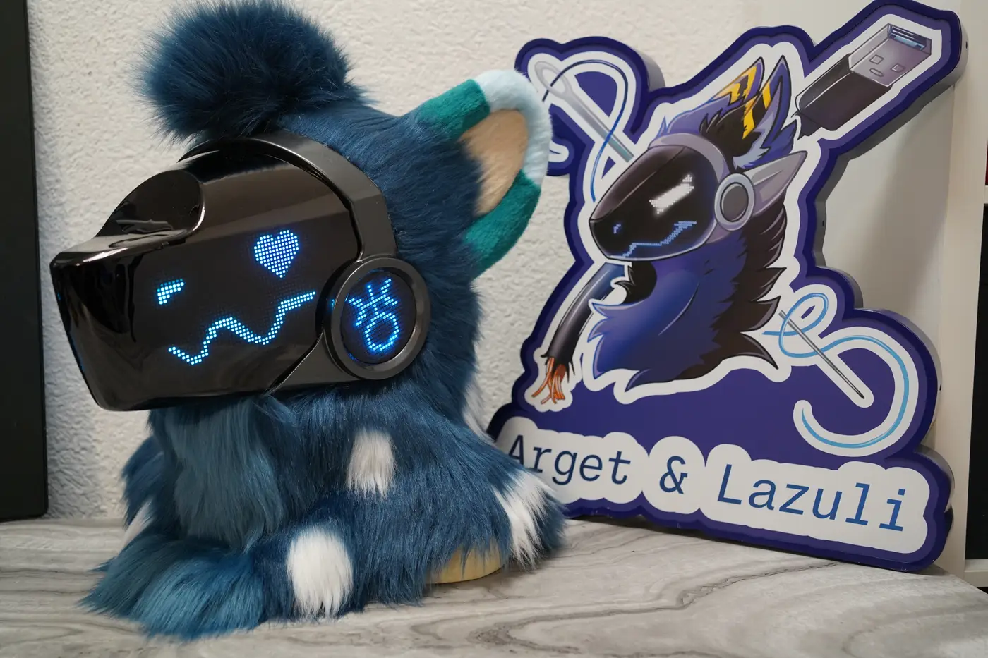 Dark teal Protogen head with a blue pixel heart eye and a zigzag mouth on the black LED visor