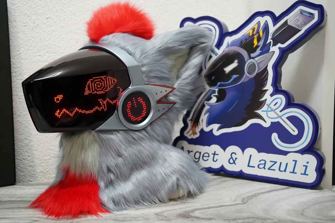 Gray Protogen head with a red pixel spiral eye and a wavy mouth on the black LED visor