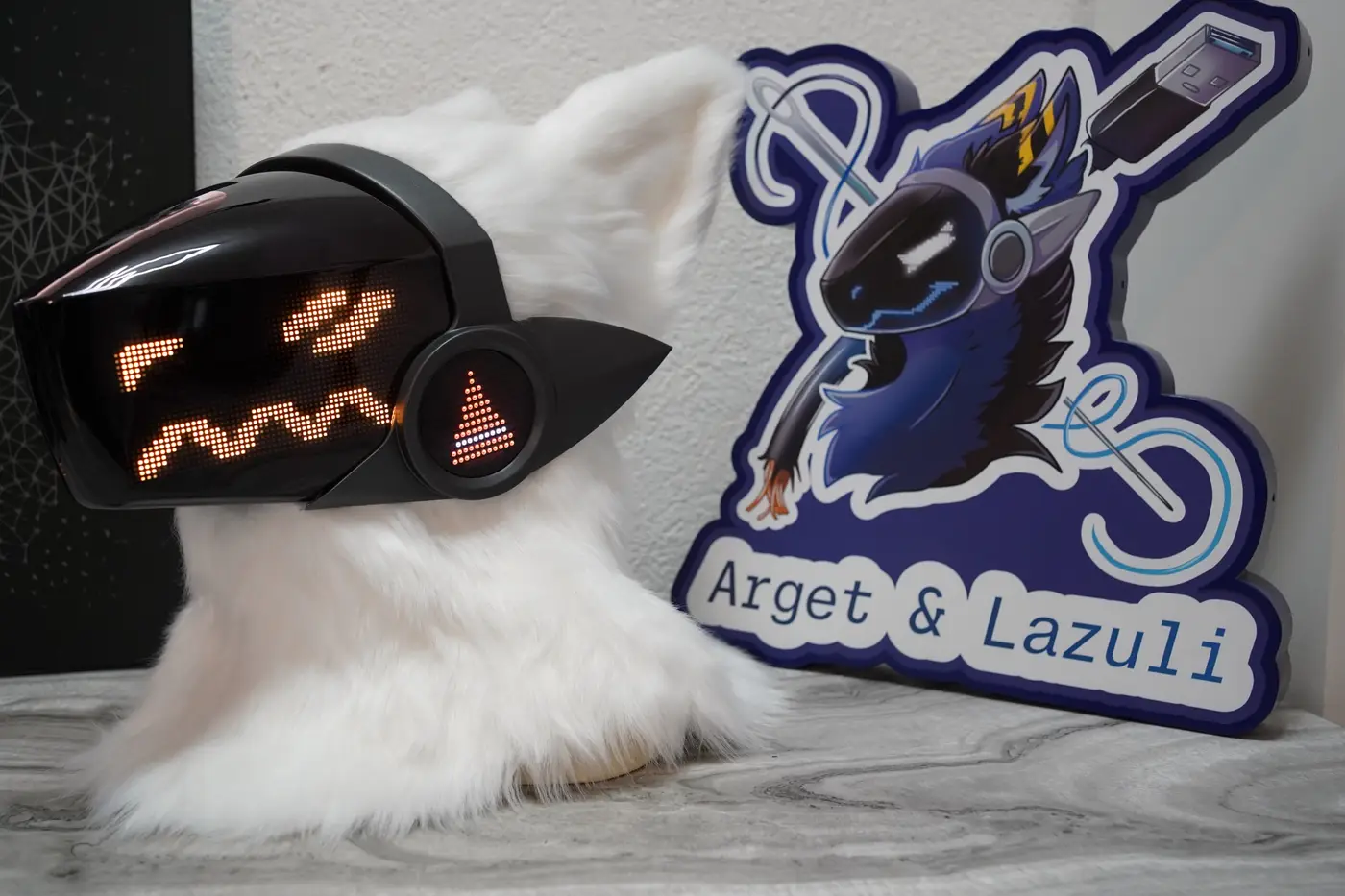 White Protogen head with one square orange eye and a jagged mouth on the LED visor