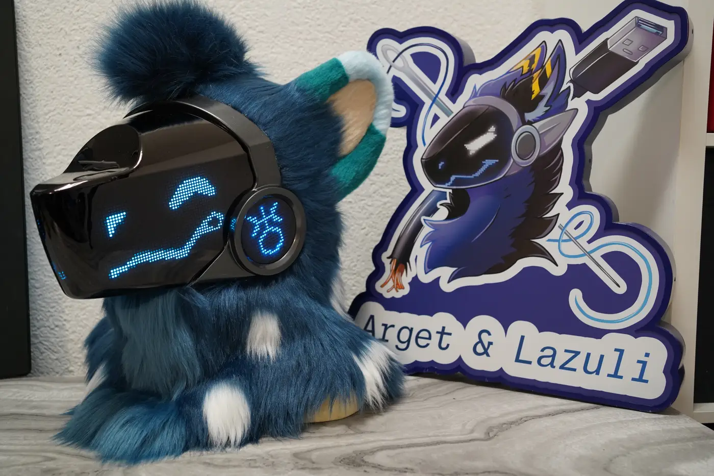 Dark teal Protogen head with arched blue pixel eyes and a long wavy mouth on the LED visor