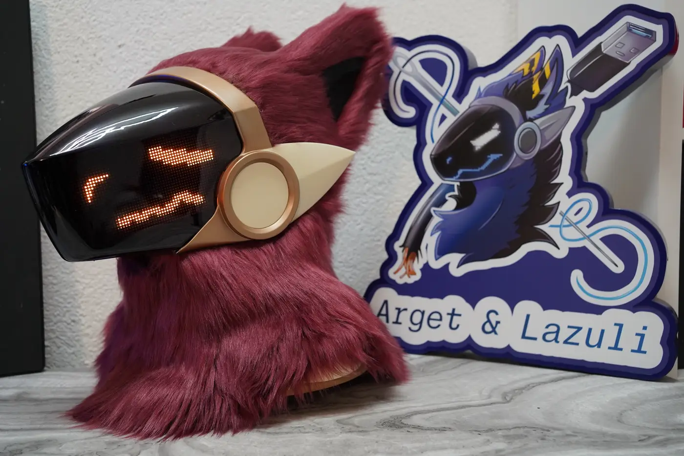 Burgundy Protogen head with straight orange eyes and a flat mouth on the LED visor