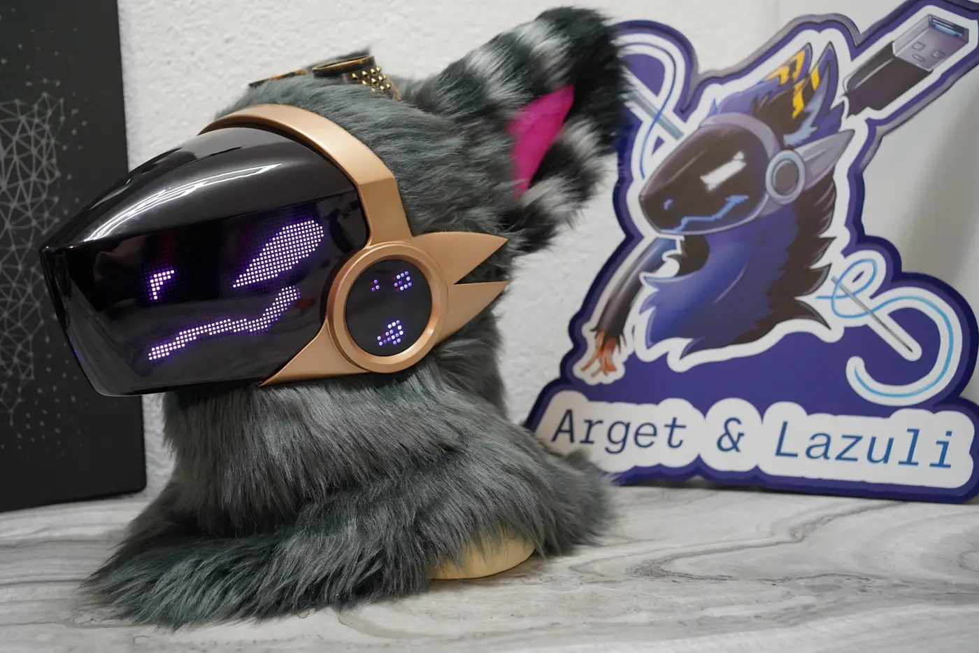 Grey Protogen head with narrow purple eyes and a wavy mouth on the LED visor