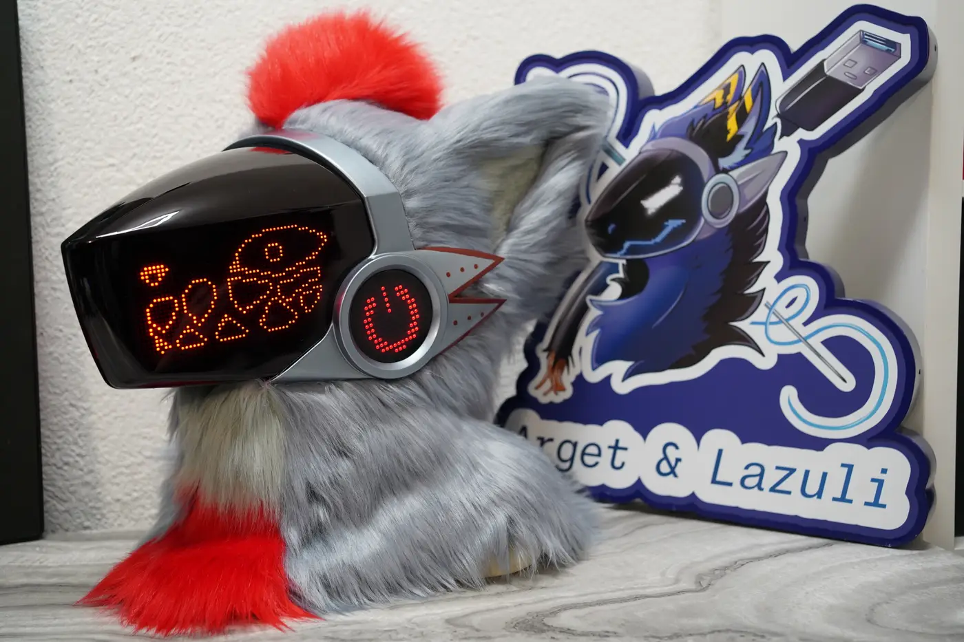 Gray Protogen head with playful red pixel doodles across the black LED visor