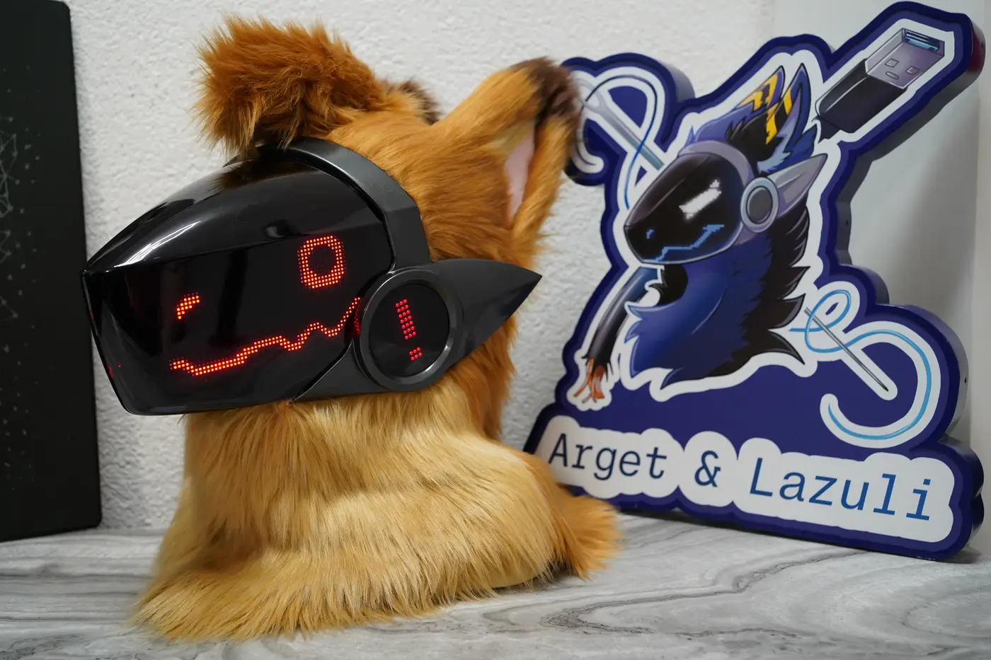 Tan Protogen head with a red winking pixel expression on the black LED visor