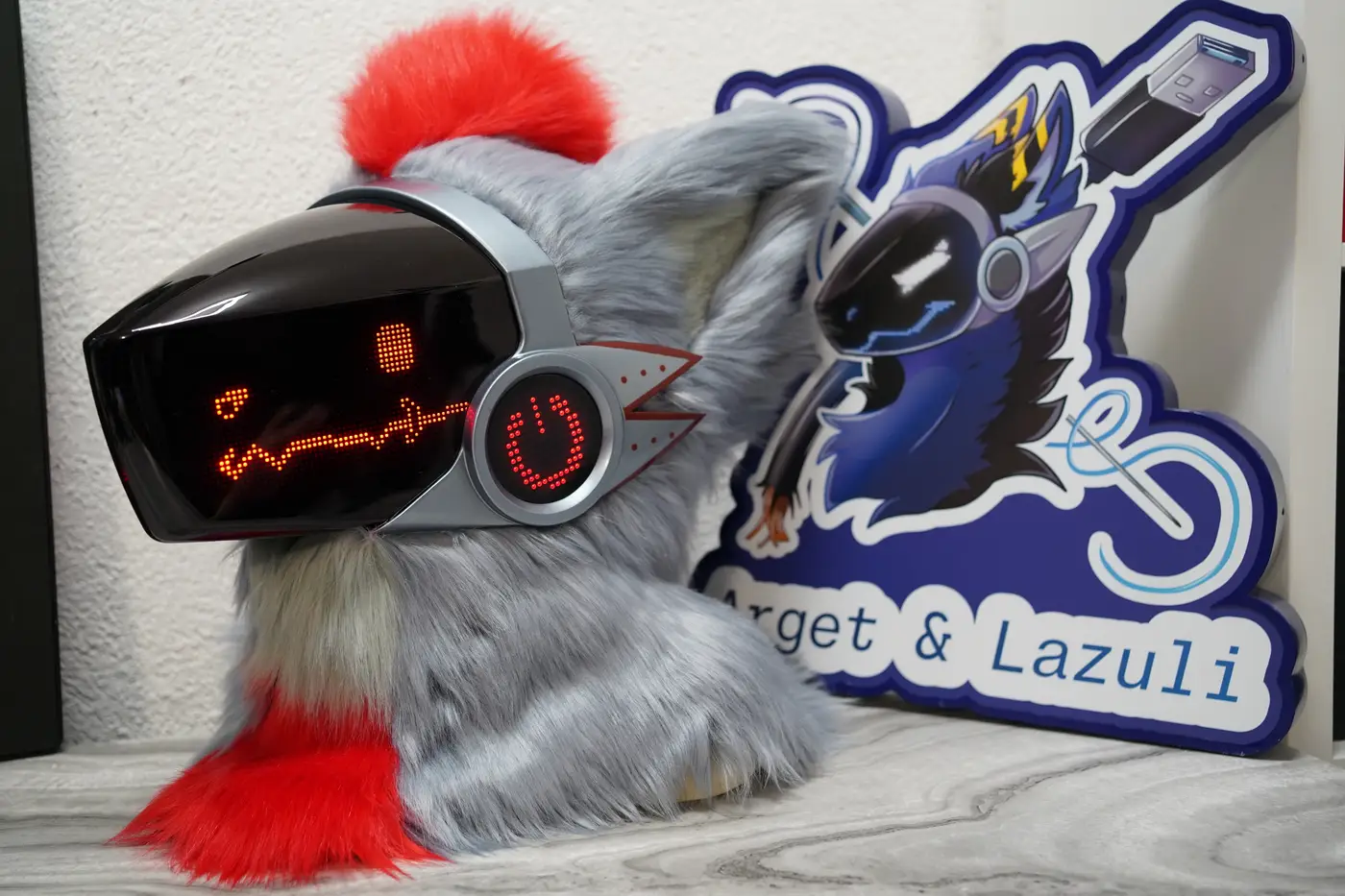 Gray Protogen head with a tall red pixel eye and a long zigzag mouth on the black LED visor