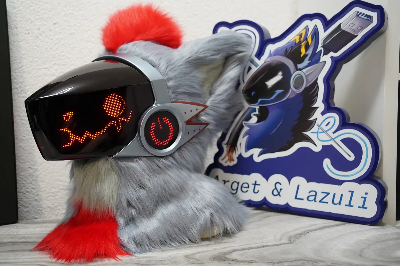 Gray Protogen head with a round red pixel eye and a wide grin on the black LED visor