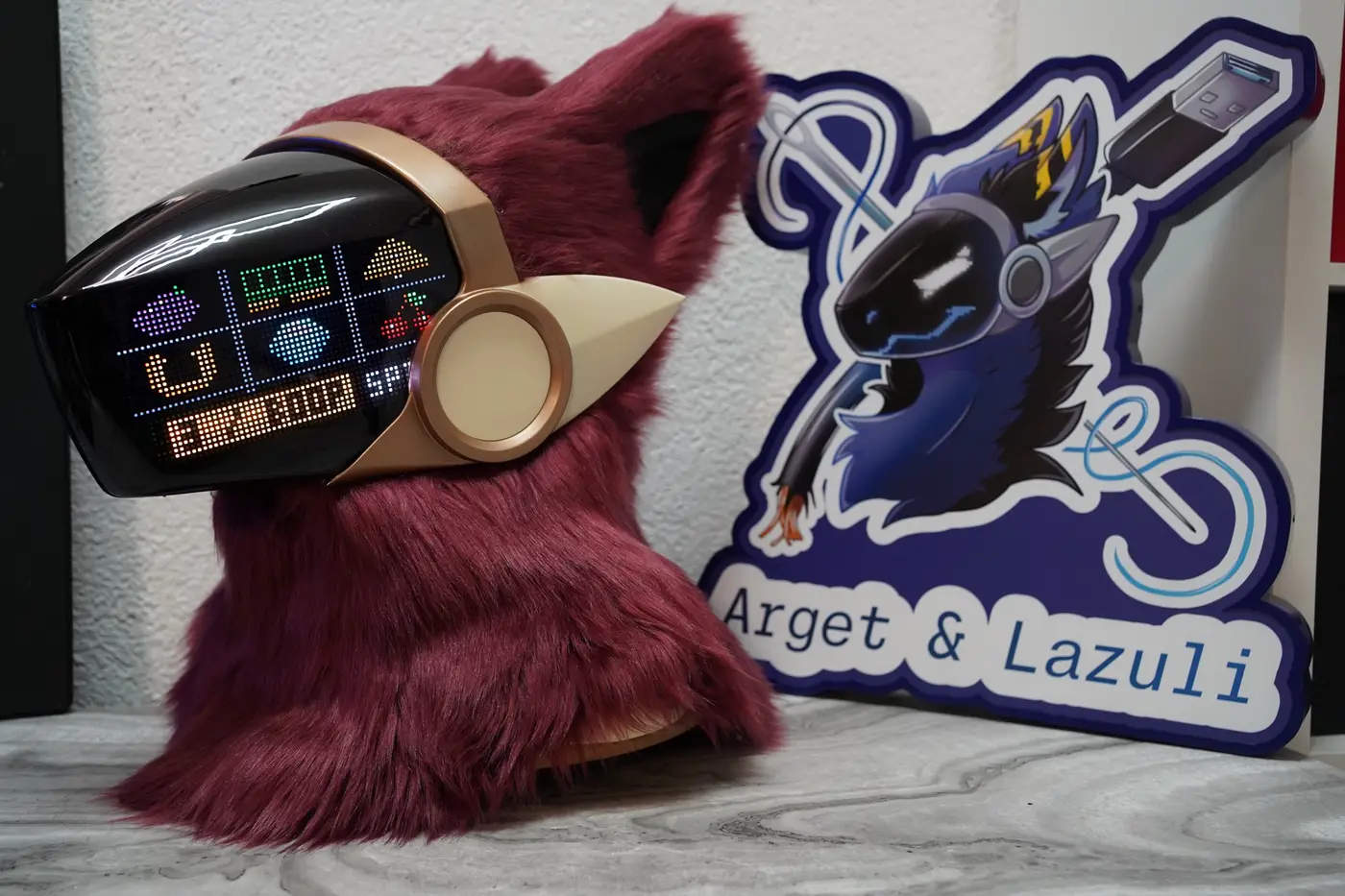 Burgundy Protogen head with colour game icons and a status bar on the LED visor