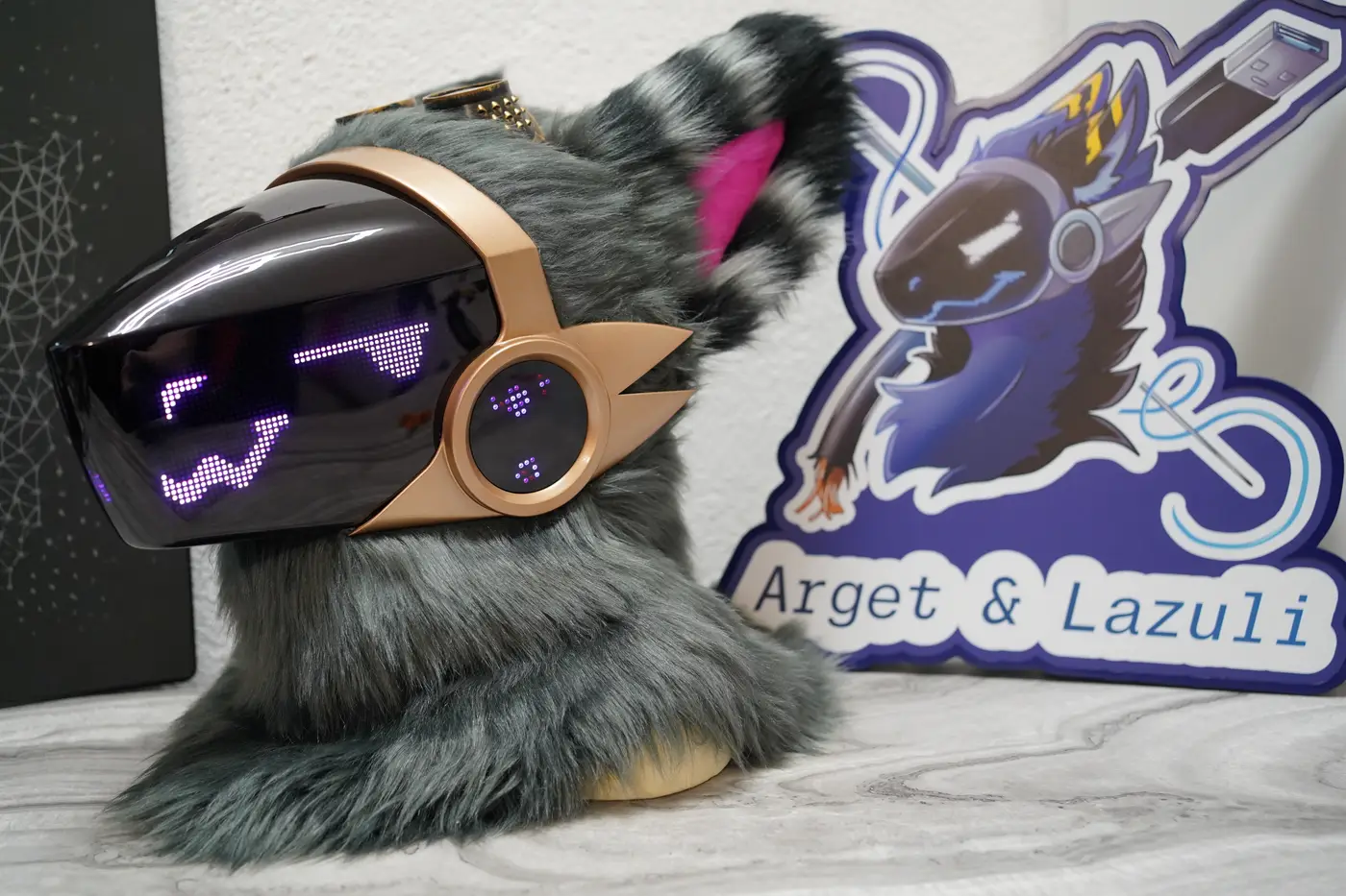 Grey Protogen head with a purple zigzag mouth on the black LED visor