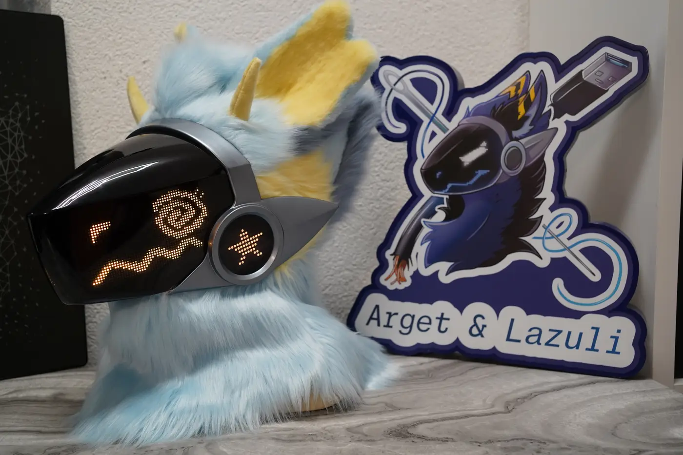 Light blue Protogen head with a yellow spiral pixel eye on the black LED visor
