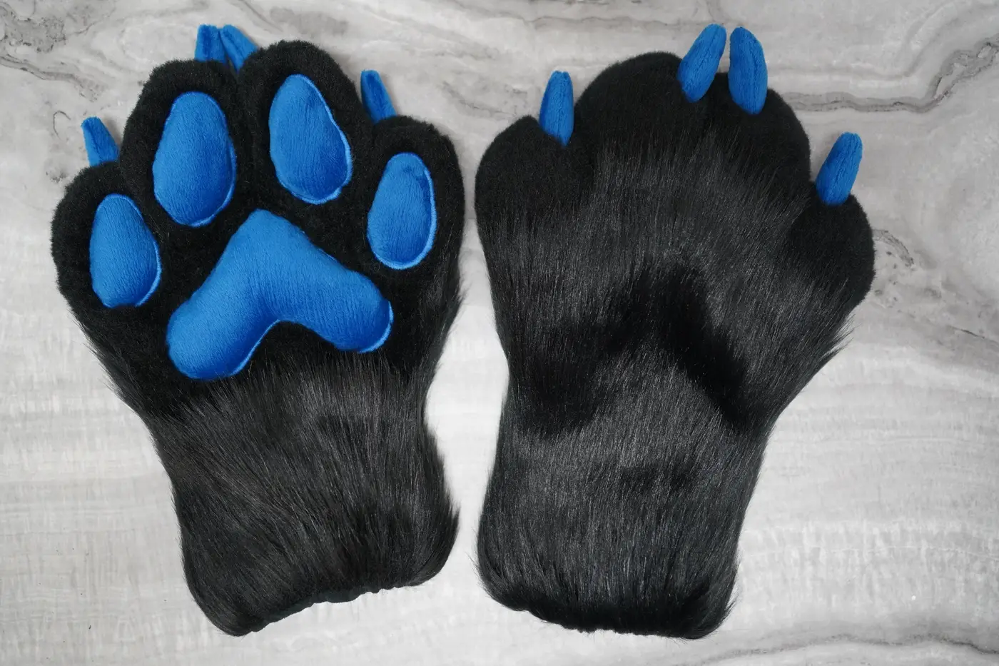 Black Protogen hand paws with blue pads and blue claws