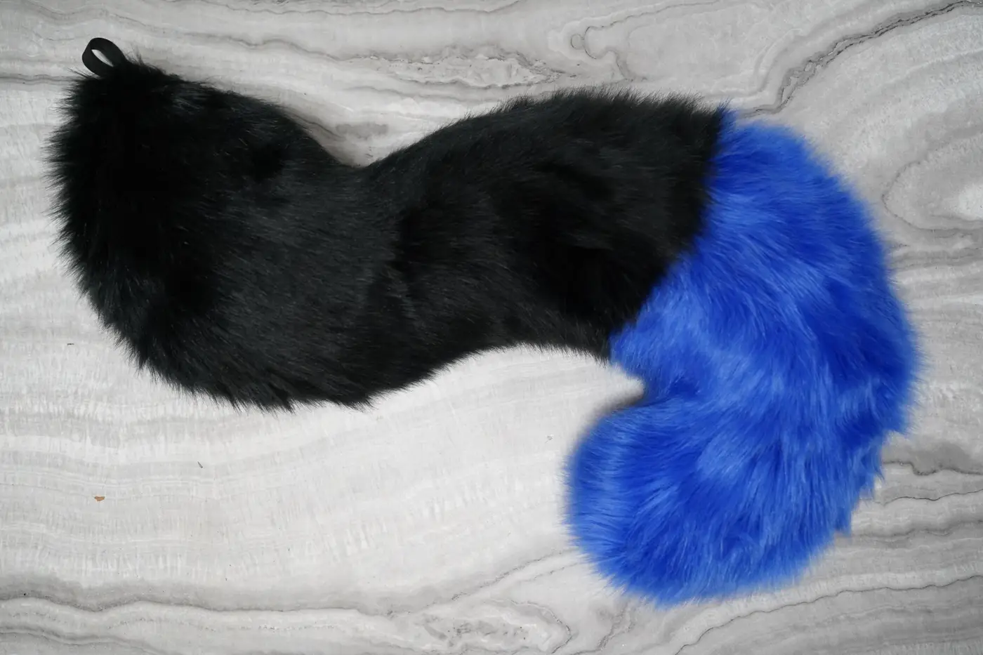 Long black Protogen tail with a bright blue tip and a curled end