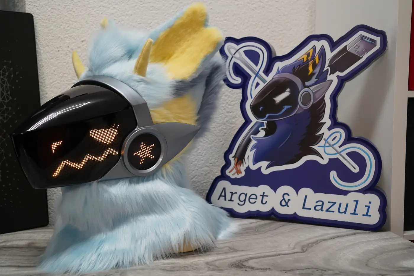 Light blue Protogen head with a sharp yellow pixel grin on the black LED visor