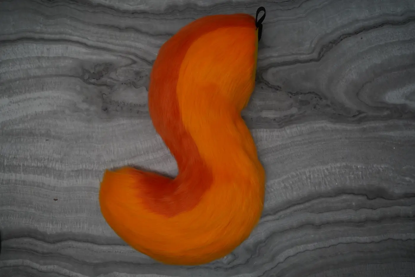 Bright orange Protogen tail with a lighter underside curved in an S shape