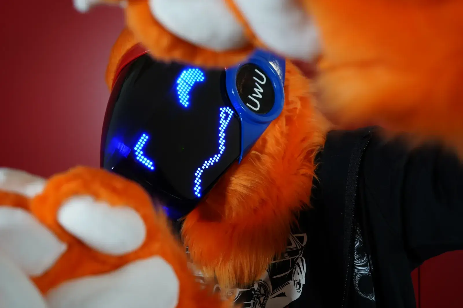Orange and white Protogen partial with blue LED pixel visor showing a UwU expression and orange mane
