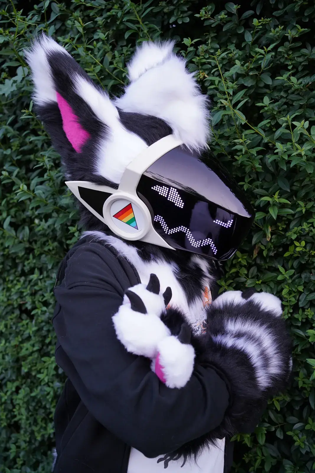 Black and white Protogen partial with a white visor showing pixel eyes and a rainbow badge on the cheek