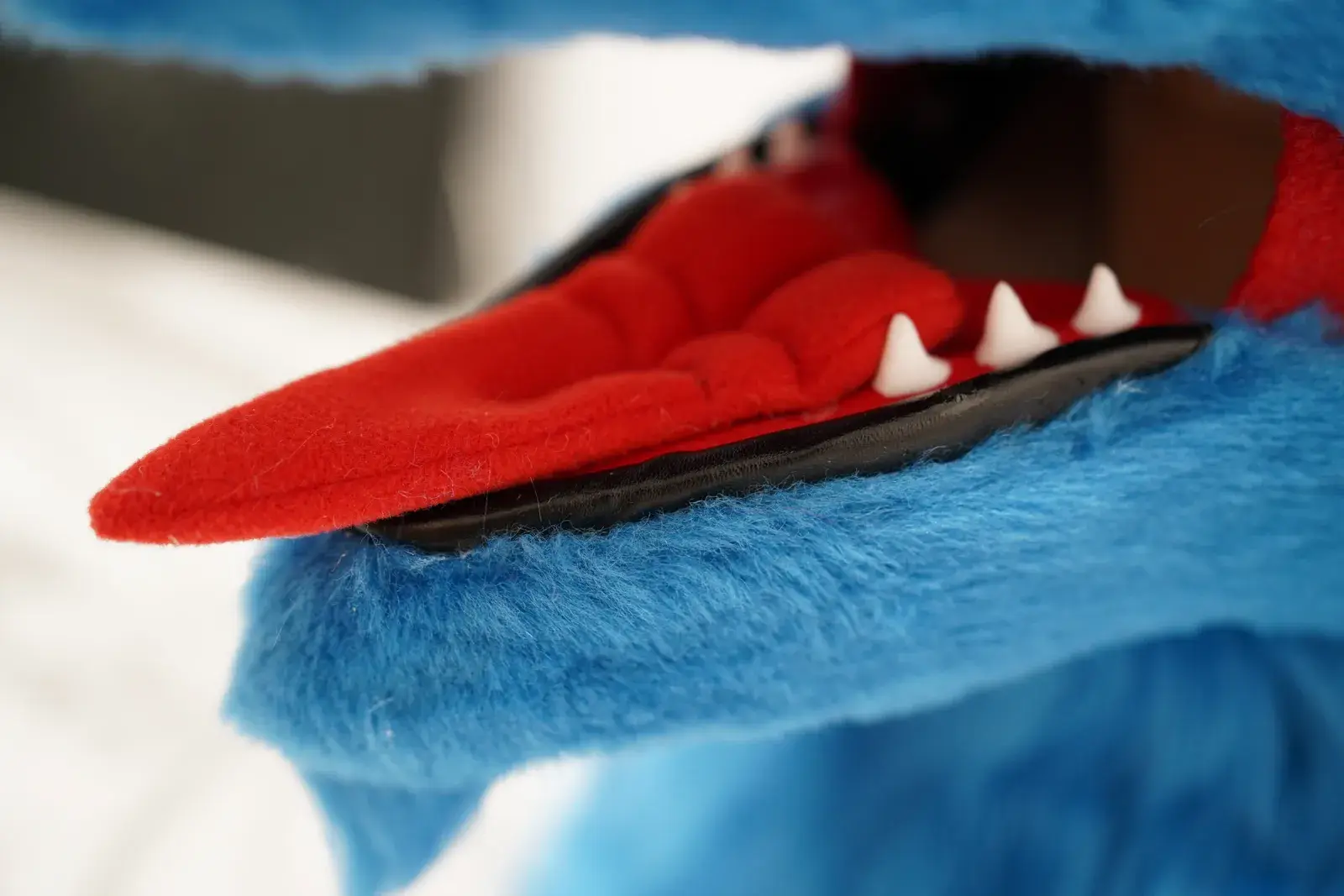 Close up of a blue fursuit open toony mouth with a red tongue and white teeth