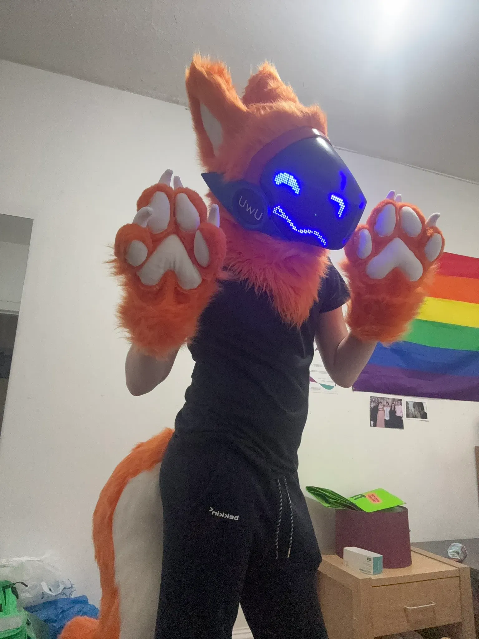 Orange fox Protogen partial with a black UwU visor and blue pixel eyes, paws raised indoors, by Arget & Lazuli