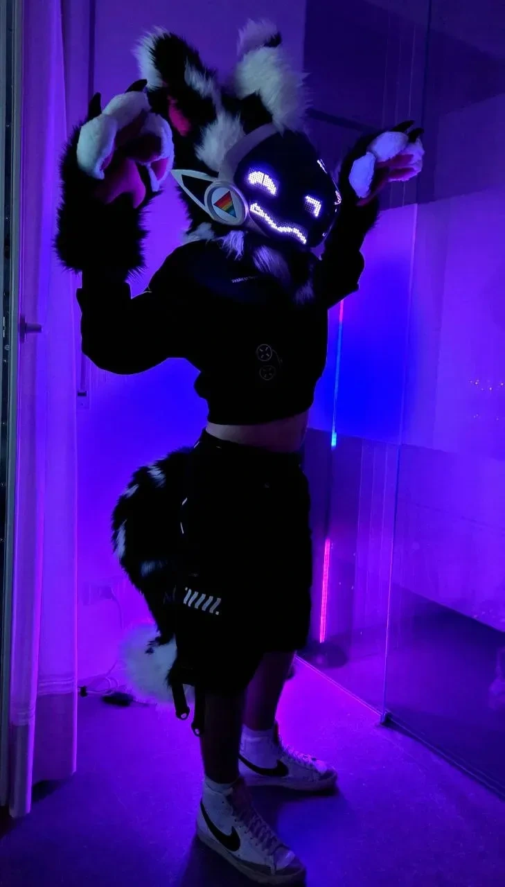 Black and white Protogen mini partial with a rainbow visor emblem, posing under purple light, by Arget & Lazuli